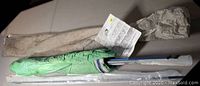 Photo showing folded green kite fabric attached to metal spar with instruction sheet and beige carrying bag.