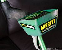 Close-up of green control housing with 'GARRETT Graphic Target Analyzer GTA 1000' printed in yellow, showing keypad on top.