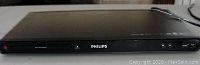 Front view of Philips DVP5990 DVD player showing power button, disc slot, and Philips logo with no display active.