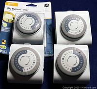 Four GE Big Button 24-Hour Mechanical Timers, one in original packaging and three loose, showing front dial sides.