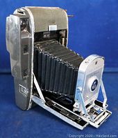 Front angled view of Polaroid Land Camera 160 showing extended bellows and metal front plate with lens.