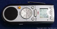 Front view of Olympus VN900 digital voice recorder showing buttons, speaker, and LCD display with status info.