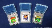 Three Nintendo Game Boy game cartridges (Baseball, Motocross Madness, Tennis) shown in open clear plastic protective cases.