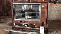 Full front view of Sunbeam kerosene heater showing metal grille, wood-grain panel and control panel with labels.