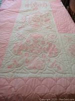View of full quilt showing central white panel with pink floral block and surrounding pink border