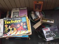 Photo of boxed games stacked, includes Twister, Front Page Challenge puzzle, jigsaw puzzle, and other boxed board games.
