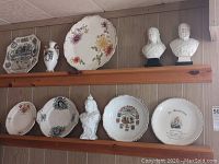 Overview of lot on two wooden plate rails showing decorative plates, vase and busts