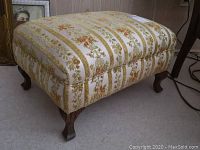 Front and top view of footstool showing floral patterned upholstery with vertical stripe design and carved wooden legs.