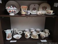 Two shelves of assorted royal commemorative china including plates, cups, saucers, and a covered tureen. Items depict Kings Edward VII and VIII with colorful royal designs.