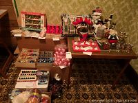Full view of the Christmas decorations lot on tables and floor with boxed ornaments, balls, figures, and candles.