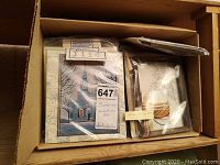 Box containing various sealed Panko kits including a snowy church design and floral pieces.