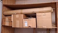 Four cardboard boxes and three rolls of Pellon fabric on a wooden shelf