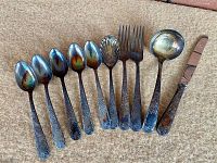 Six teaspoons, sugar shell spoon, two forks, sauce ladle and table knife in patterned handles
