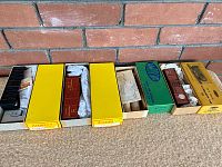 Four HO scale train cars in original vintage boxes displayed side by side.