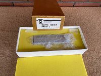 Opened gold embossed box showing brass locomotive secured in yellow foam liner