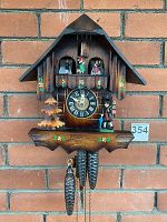 Frontal view of entire chalet-style cuckoo clock hanging against brick wall