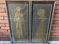 Photo showing both framed brass rubbings side by side against brick background.