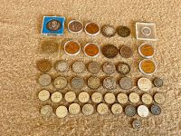 Overview of 46 assorted coins of varying size, color, and condition placed on fabric surface.