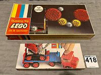 Top view of the 1960s Lego Gears set box (Gears 001) featuring gear graphics and the vintage Lego logo, along with the 1971 Lego Crane with Float Truck box showing a red and blue crane vehicle.