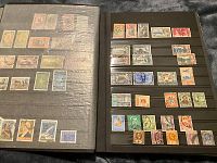 Open album showing two pages with multiple stamps of different countries and denominations, some used, some mint