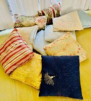 Multiple decorative throw pillows arranged together showing variety in color, pattern, and fabric texture.