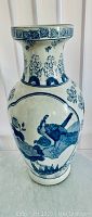 Full side view of the vase showing bird and floral design in blue on white ceramic.
