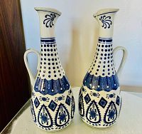 Two tall blue and white ceramic containers with handles and spouts, standing side by side showing detailed blue geometric and floral patterns on white ceramic.
