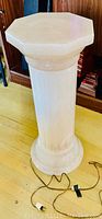 Full view of the antique light-up lamp stand showing its columnar base and octagonal top piece on a wooden floor, electrical cord visible.
