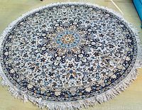 Full view of the round rug laid flat on the floor showing the detailed pattern and fringed edges