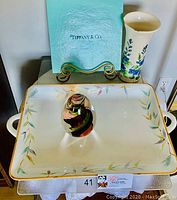 Full view of the Tiffany & Co. Bamboo tray with floral design, Este Ceramiche vase with blue flowers, and Murano glass egg sculpture, plus Tiffany blue folder in background.