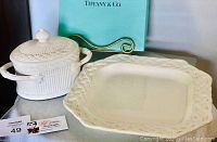 White ceramic Tiffany & Co. tray with braided edge design and a ceramic container with lid and handles, displayed with Tiffany & Co. box.