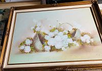 Framed painting showing white flowers arranged in a basket with a soft neutral background.