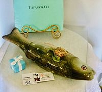 Porcelain Tiffany fish container next to Tiffany blue gift box, showing side profile and pinecone lid decoration.