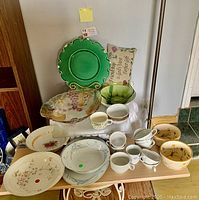Overhead photo showing entire lot of mixed fine china plates, bowls, cups, and decorative green glass bowls and plate.