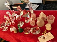 Overview of all glass and crystal items on red cloth including various bottles, candle holders, frosted vases, and decorative statues