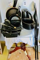 Photo of black kitchen items including electric grill pans, coffee pot, utensils, and dish drainer on top of a white cloth.