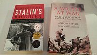Front covers of two books: "Stalin's Daughter" shows Stalin with a child, red and black colors, "A Writer at War" depicts Soviet soldiers during WWII.
