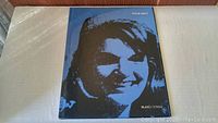 Front cover of the art book showing a blue-toned screen print image of Jacqueline Kennedy Onassis, with title and author information