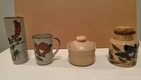 Front view of 4 ceramics including tall vase, mug, lidded pot, jar
