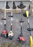 Four grass trimmers side by side showcasing size and overall condition.