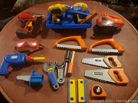 Top-down photo of entire toy power tool set, showing tools arranged around carrying case on a wooden table.