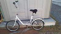 White ROG Pony folding bike standing in front of storage shed