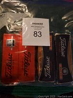 Photo showing multiple unopened boxes of Titleist golf balls including Pro V1, AVX, and Velocity models in original packaging.