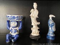 Front view of three Asian porcelain figurines: monkey holding bowl, white standing figure, bird-headed character.