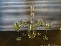 Full set photo showing the decanter and four matching glasses, displayed with grape vine design on clear glass.
