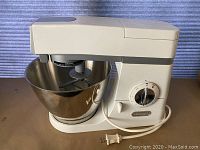 Front view of white De'Longhi Chef Food Mixer with attached 5QT stainless steel bowl and cord coiled on the base.