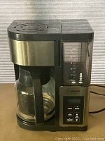 Full view of coffee maker showing glass carafe, water reservoir and control panel.