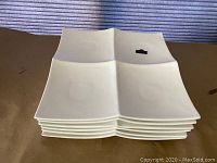 Stack of six white square sectioned heavy china plates showing thickness and size.