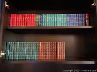 Books arranged on shelves showing full set of 63 fiction hardcover books in multiple colors with gold embossed titles.
