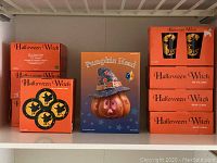 Shelved boxed Halloween Witch plates, mugs, and pumpkin head centerpiece showing original packaging and quantity